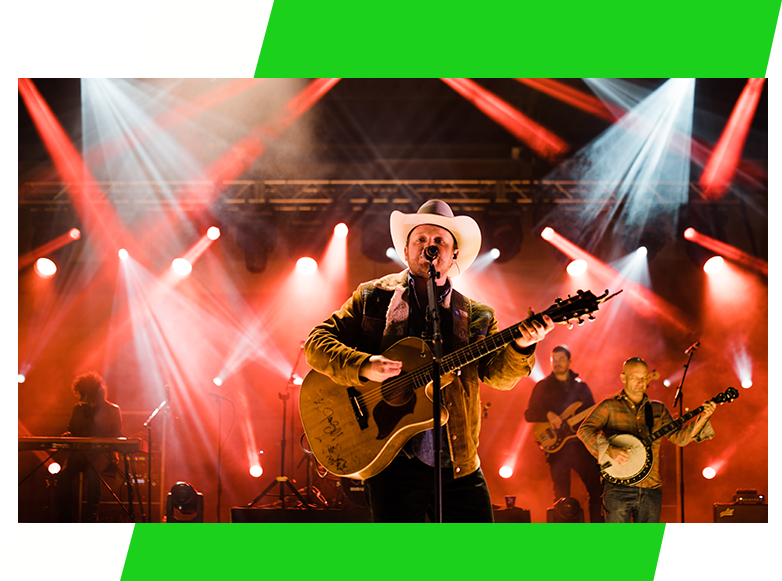 A man in cowboy hat playing guitar on stage.